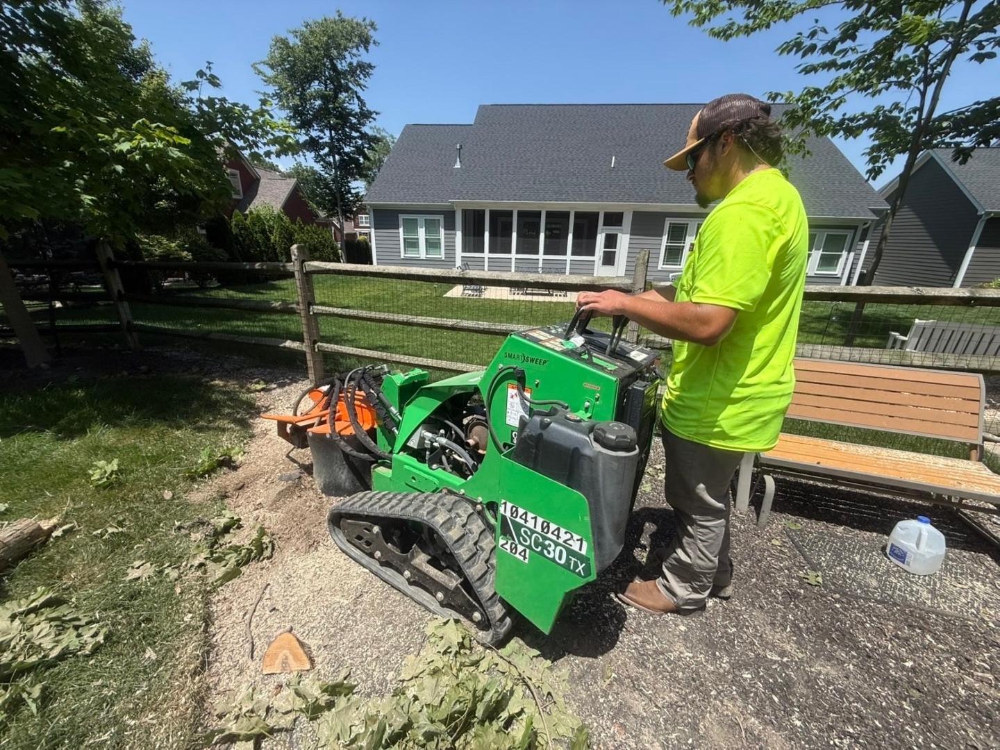 Hole in 1 crew member grinding a tree stump with a walk-behind stump grinder in a Columbus-area backyard